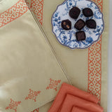 Decorative table setting with a plate of chocolates, , and orange napkins on a block printed tablerunner